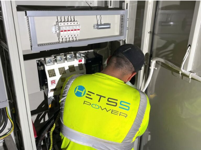 HETSS certified electrician working inside a commercial electrical switchgear panel in Aruba